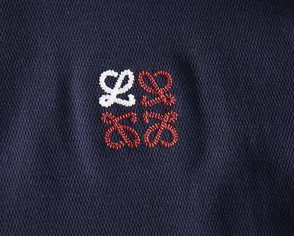 Close-up of embroidered logo detail on navy polo shirt fabric
