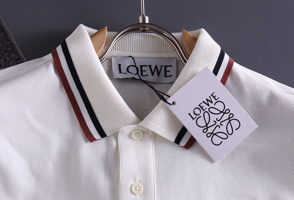 Close-up of white polo shirt collar with striped detail and brand tag on hanger
